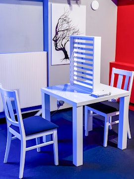 Two chairs and a table with an optical illusion exhibit at DeJa Vu Museum.