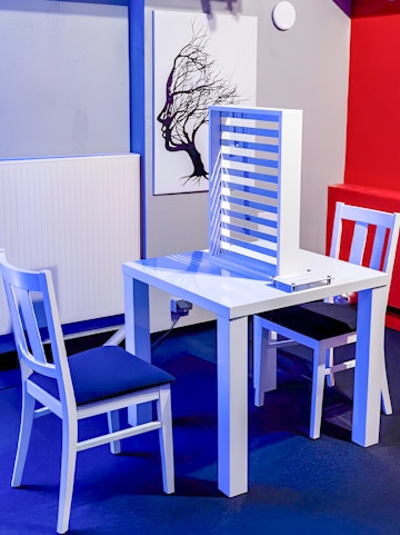 Two chairs and a table with an optical illusion exhibit at DeJa Vu Museum.