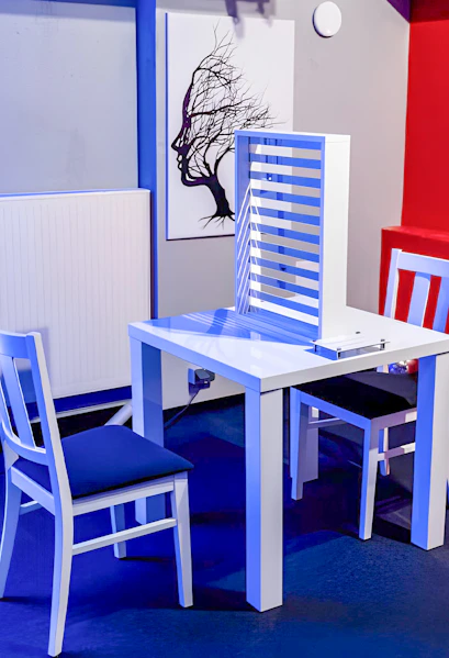 Two chairs and a table with an optical illusion exhibit at DeJa Vu Museum.