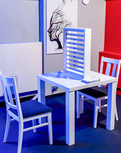 Two chairs and a table with an optical illusion exhibit at DeJa Vu Museum.