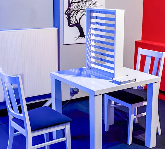 Two chairs and a table with an optical illusion exhibit at DeJa Vu Museum.