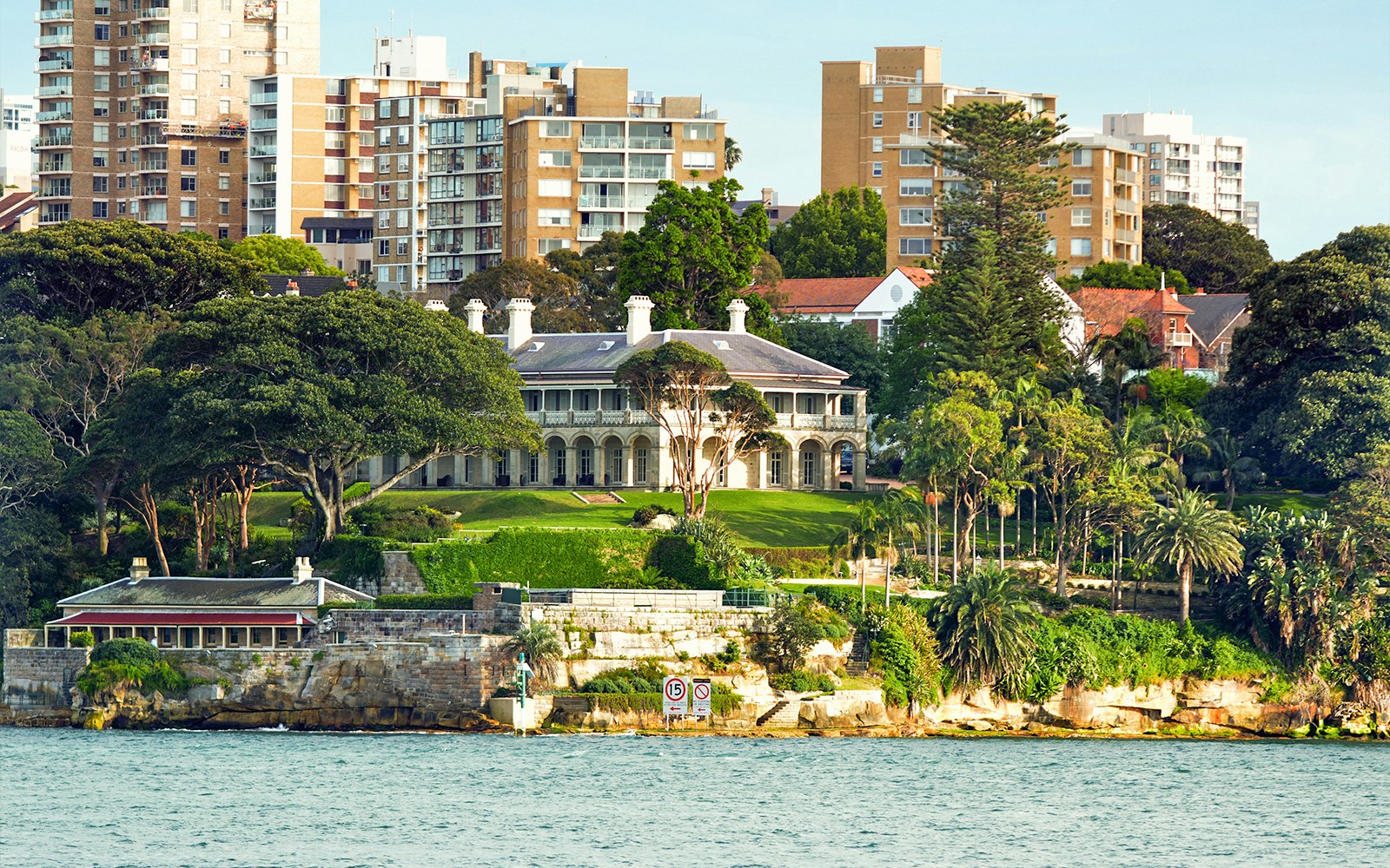 Historic mansion and gardens on Sydney Harbour with city skyline in the background.