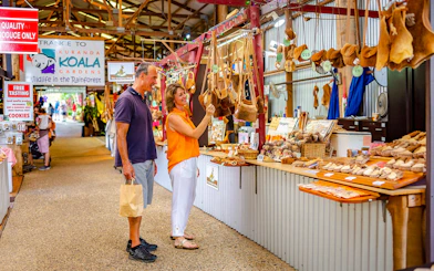 Kuranda market stall with tourists browsing local crafts on Scenic Train and Skyrail Kuranda Tour.