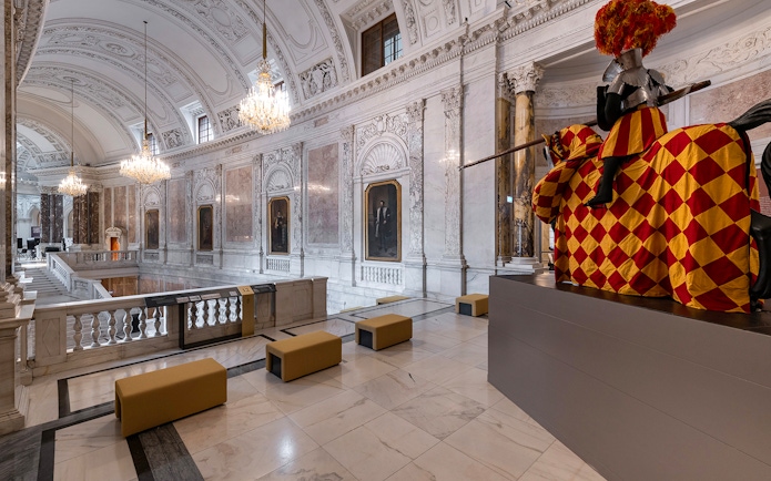 Interior of New Hofburg Palace in Vienna with ornate ceilings and knight statue.