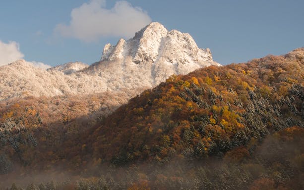 Snow-capped mountain and autumn forest near Jozankei Mori No Uta Onsen.