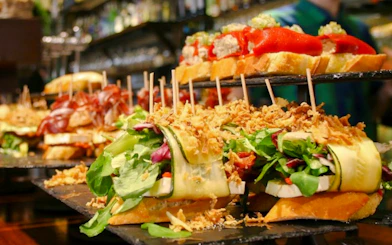 Pintxos assortment at a bar in San Sebastian, featuring fresh vegetables and cured meats.
