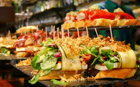 Pintxos assortment at a bar in San Sebastian, featuring fresh vegetables and cured meats.