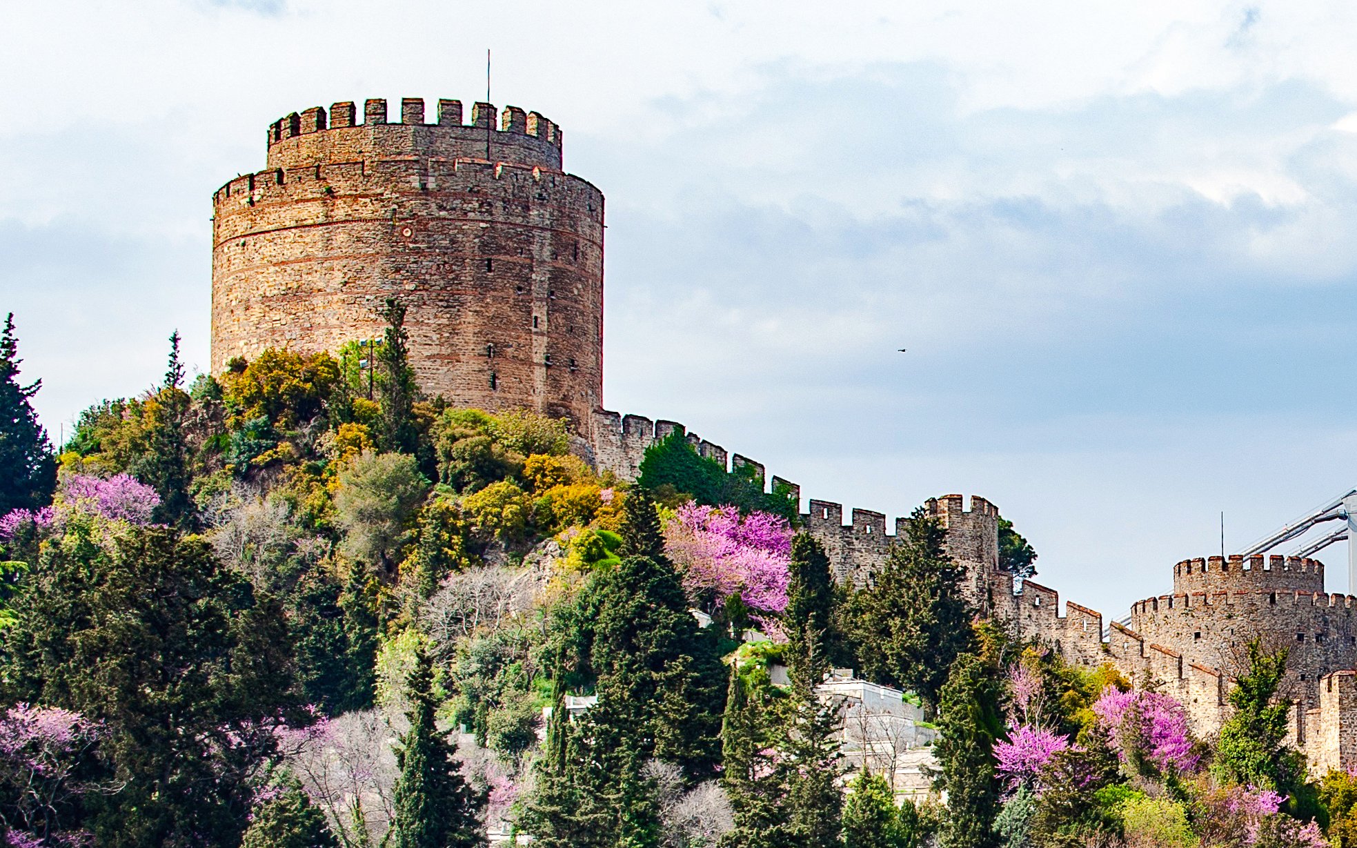 Rumeli Fortress viewed from Bosphorus Lunch Cruise, surrounded by lush greenery and blooming trees.