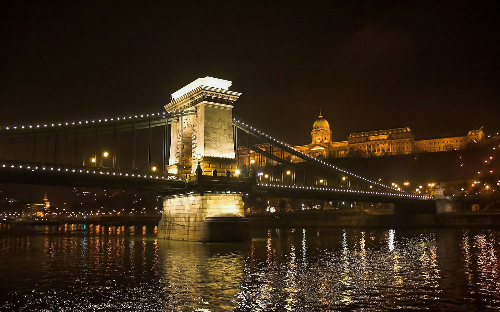 Chain Bridge illuminated at night, viewed from a Danube River sightseeing cruise in Budapest.