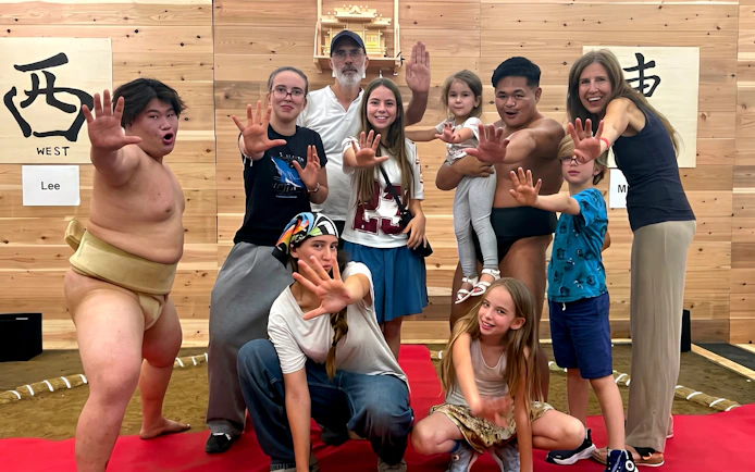 Group posing with sumo wrestlers in Kyoto dojo.