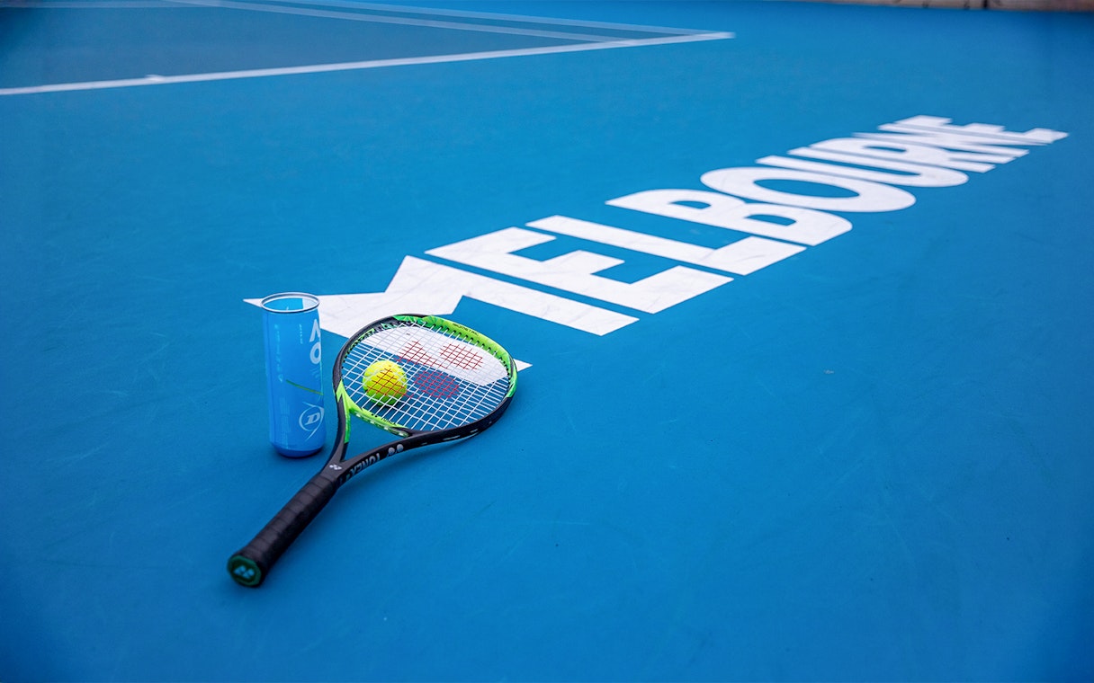 Tennis racket and ball on Melbourne court, part of Sports Lovers Day Tour.