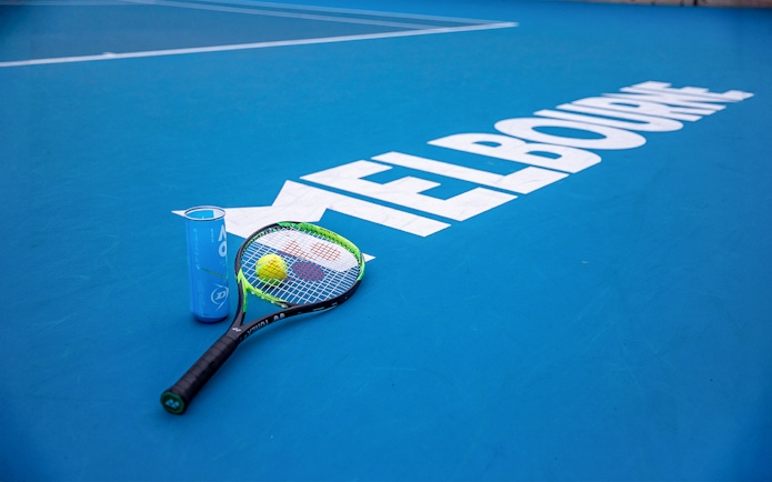 Tennis racket and ball on Melbourne court, part of Sports Lovers Day Tour.
