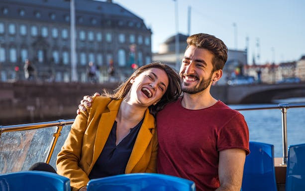 Couple enjoying a boat tour on a sunny day during a hop-on hop-off bus tour.