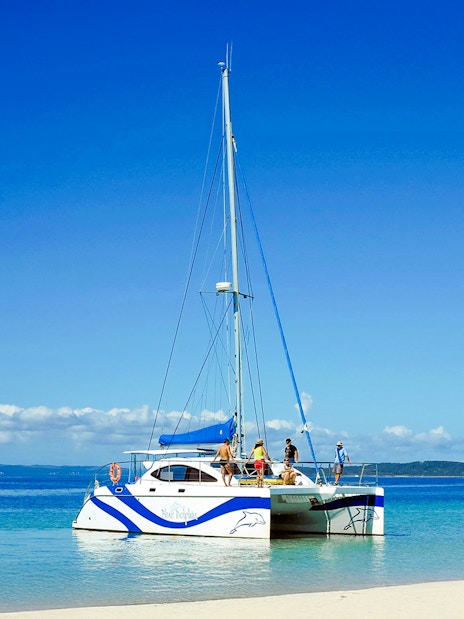 Catamaran sailing near Fraser Island, K'gari with people on deck, clear blue water.