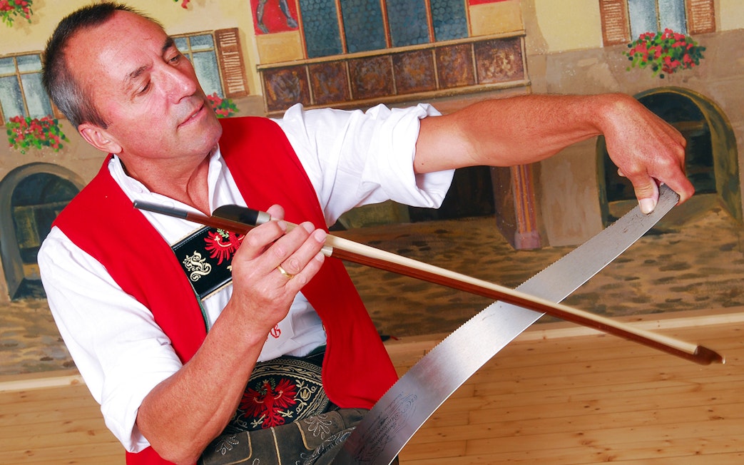 Man playing musical saw at Tyrolean Evening Folk Show with Gundolf Family.