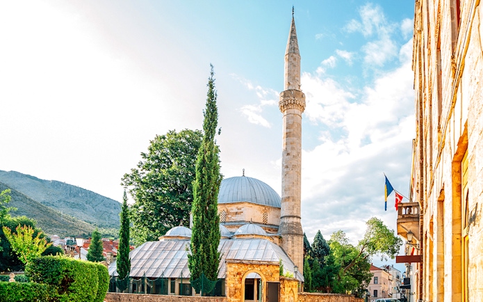 Karagoz Bey Mosque with minaret and surrounding greenery in Mostar, Bosnia and Herzegovina.