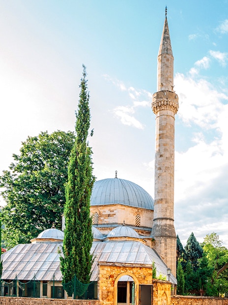 Karagoz Bey Mosque with minaret and surrounding greenery in Mostar, Bosnia and Herzegovina.