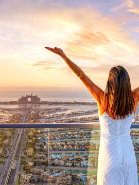 Woman enjoying sunset view of Palm Jumeirah and Atlantis, Dubai from a high vantage point.