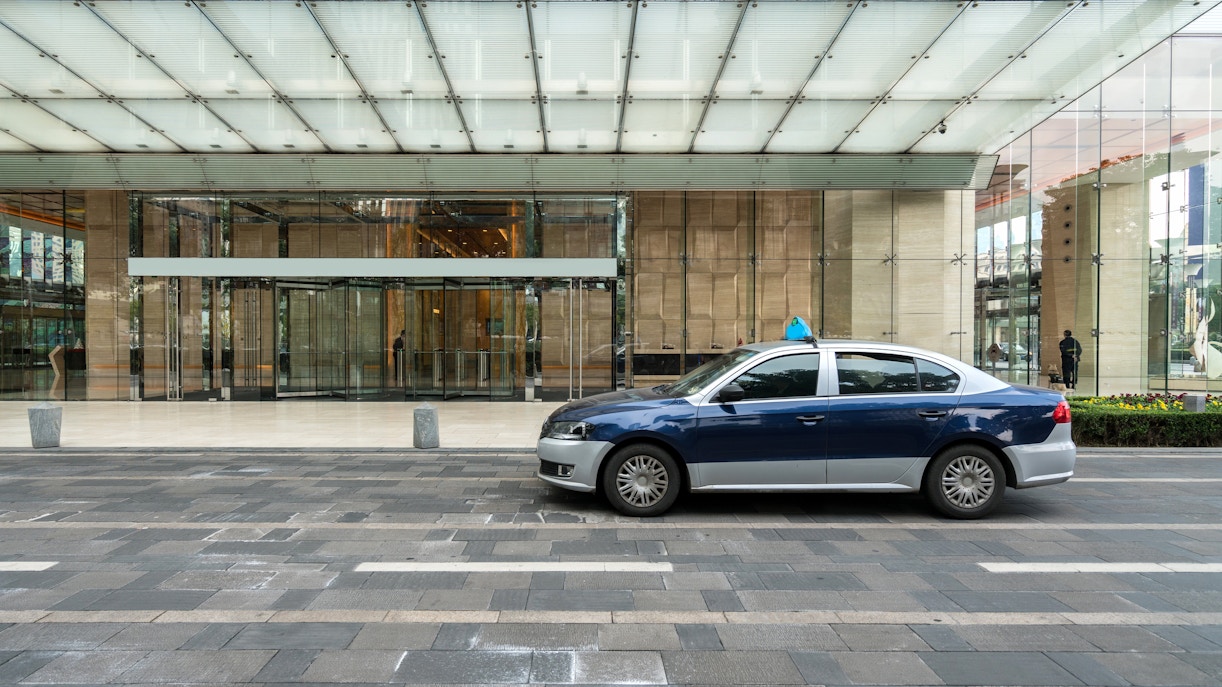 Taxi parked in front of a modern glass building