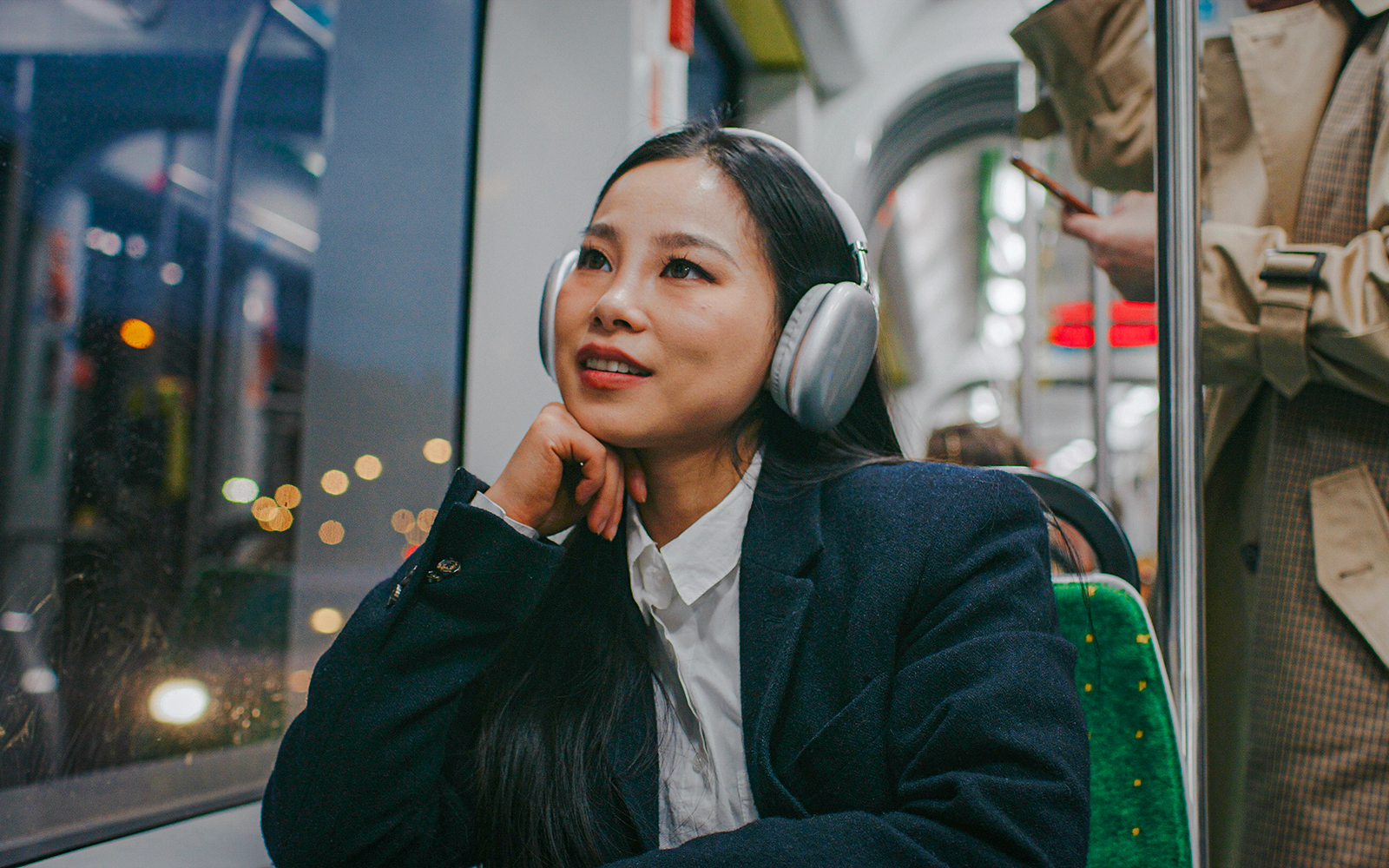 Woman listening to music on night bus.