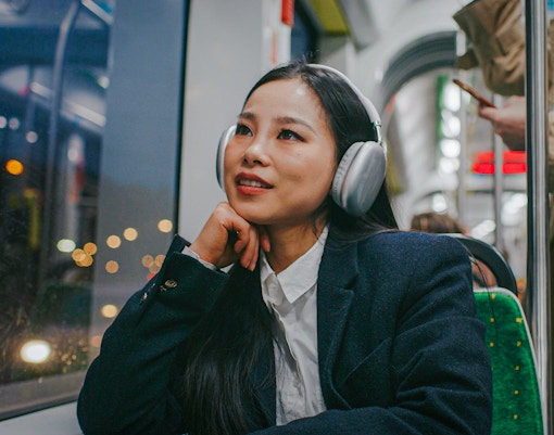 Woman using audio guide on night bus tour in city.