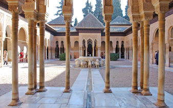 Court of the Lions, Alhambra, featuring central fountain with lion sculptures and intricate arches.