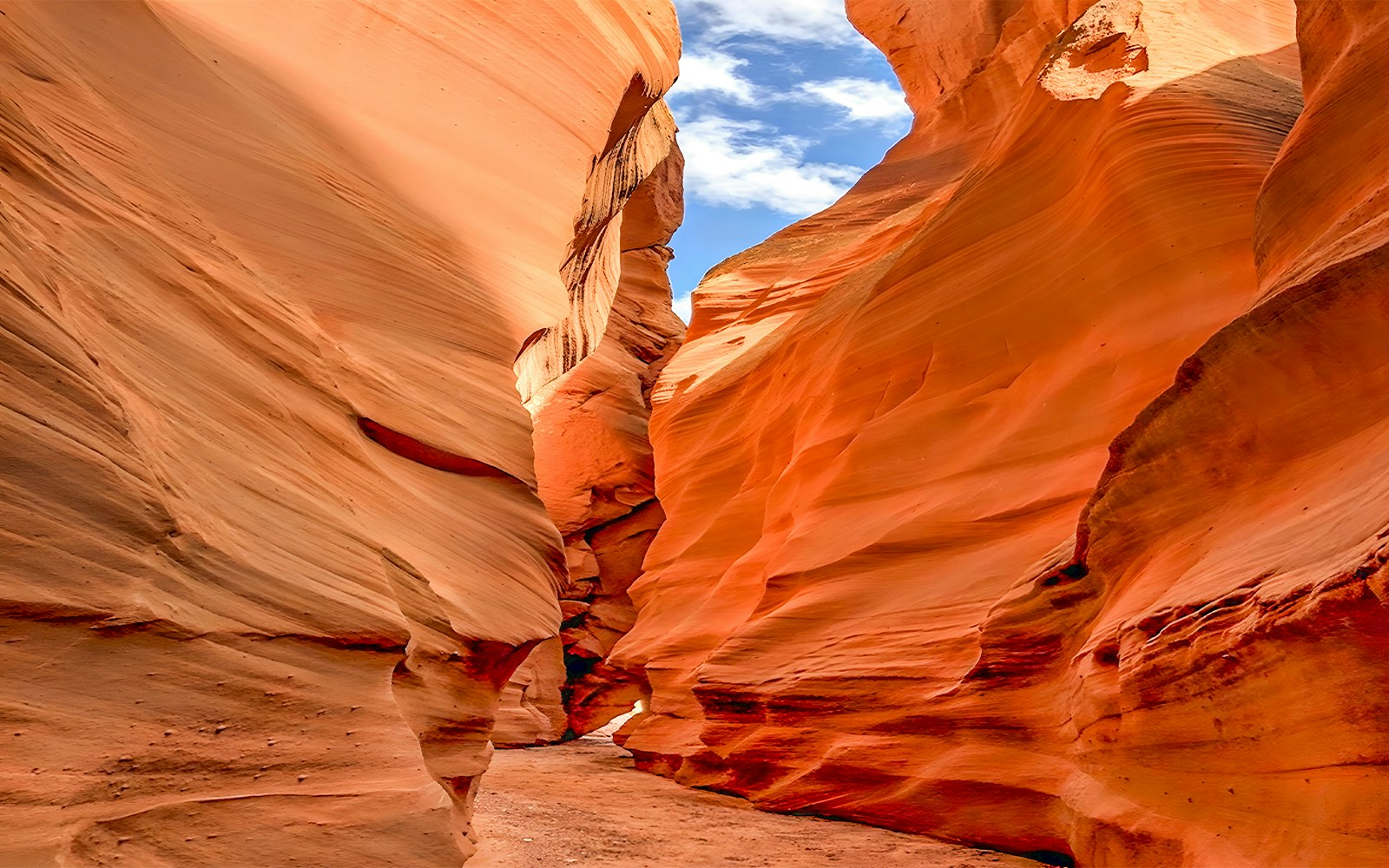 Antelope Valley Canyon narrow passage with red sandstone walls under blue sky.