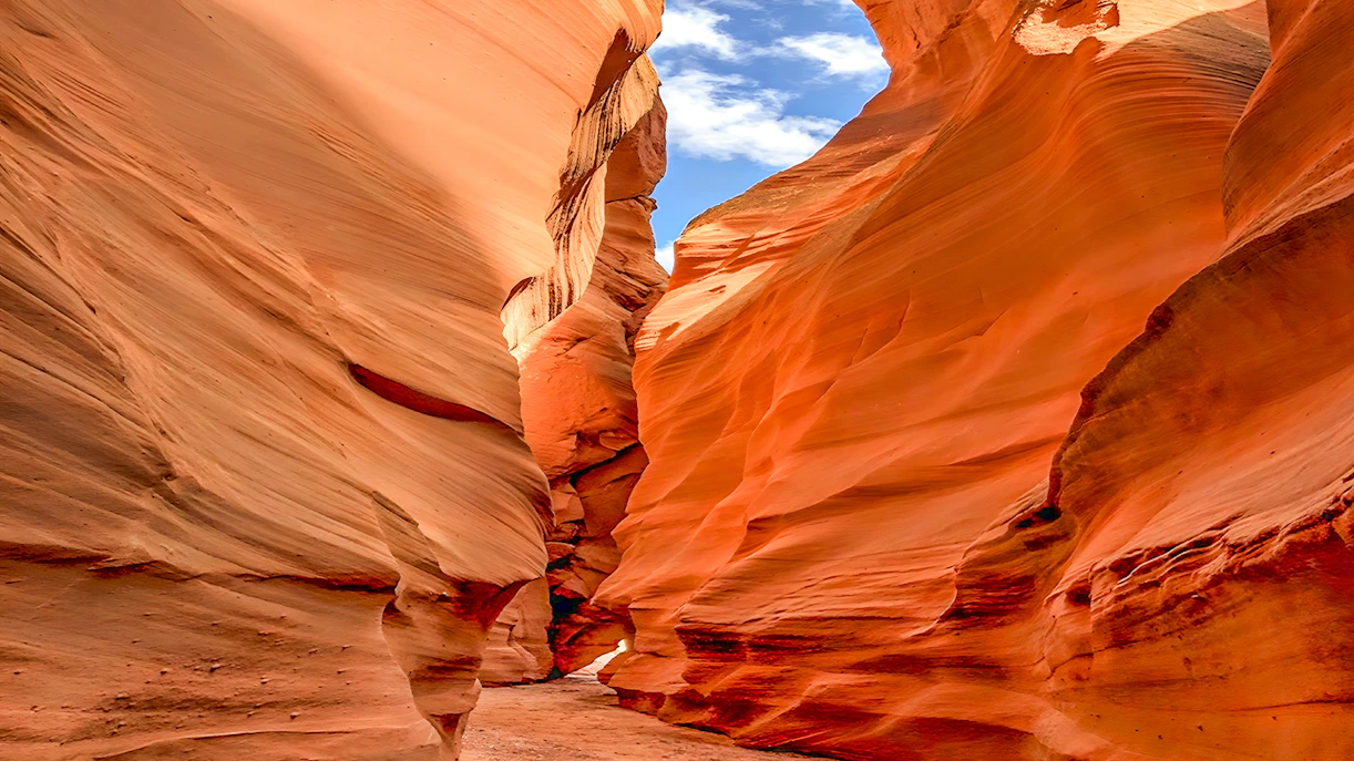 Antelope Valley Canyon narrow passage with red sandstone walls under blue sky.
