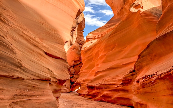 Antelope Valley Canyon narrow passage with red sandstone walls under blue sky.
