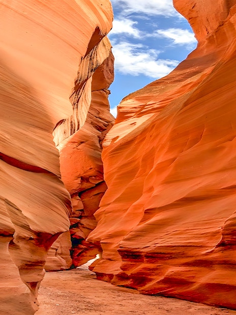 Antelope Valley Canyon narrow passage with red sandstone walls under blue sky.