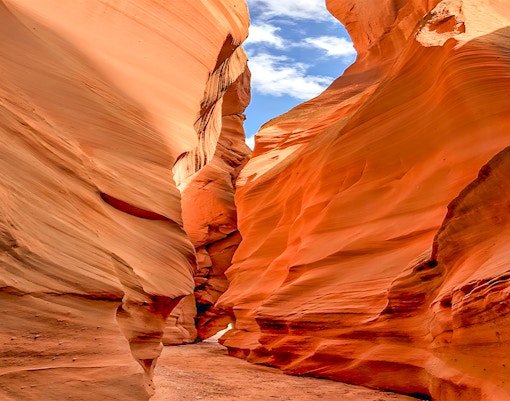 Antelope Valley Canyon narrow passage with red sandstone walls under blue sky.