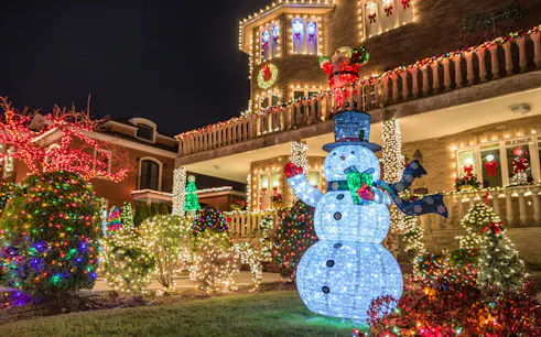 Christmas lights display with snowman and decorated house on New York bus tour.