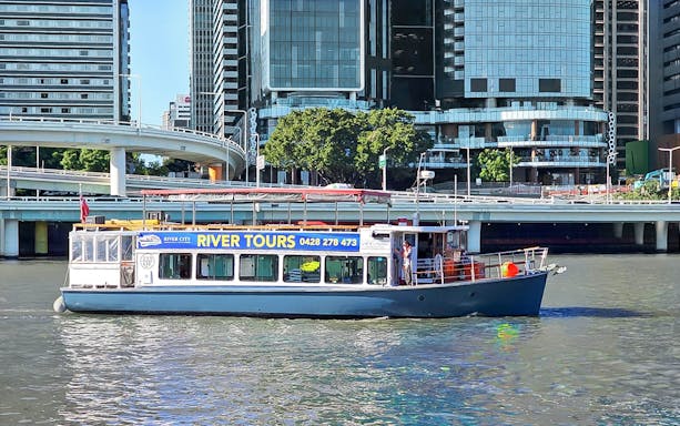 Boat cruising on Brisbane River with city buildings in the background.