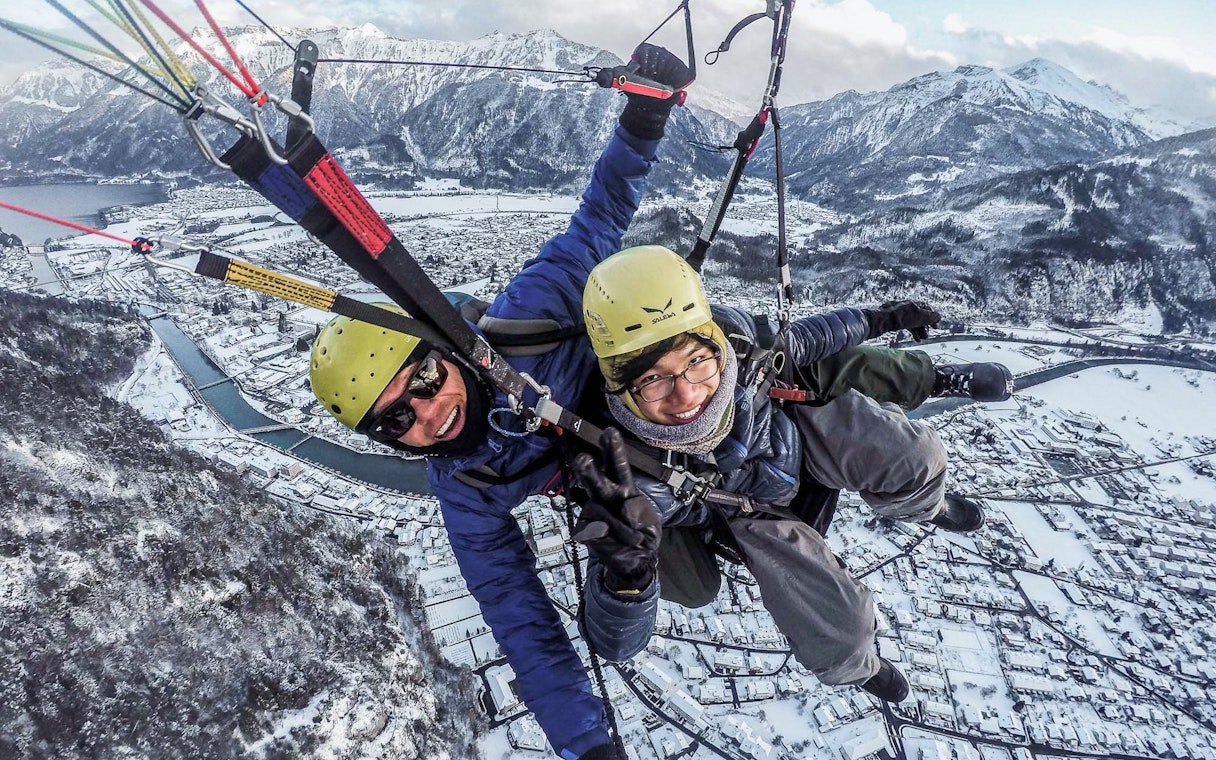 Paragliding over snowy Interlaken with mountains in the background during winter.
