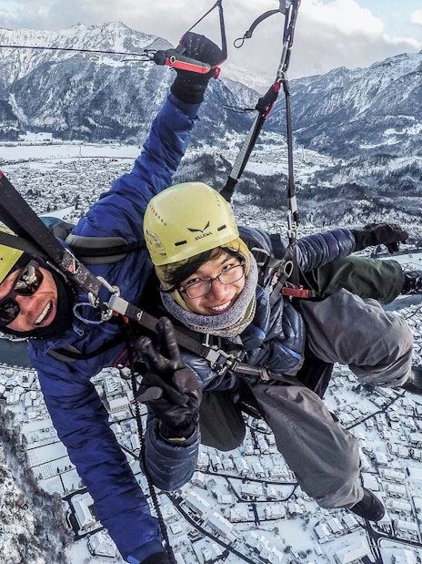 Paragliding over snowy Interlaken with mountains in the background during winter.