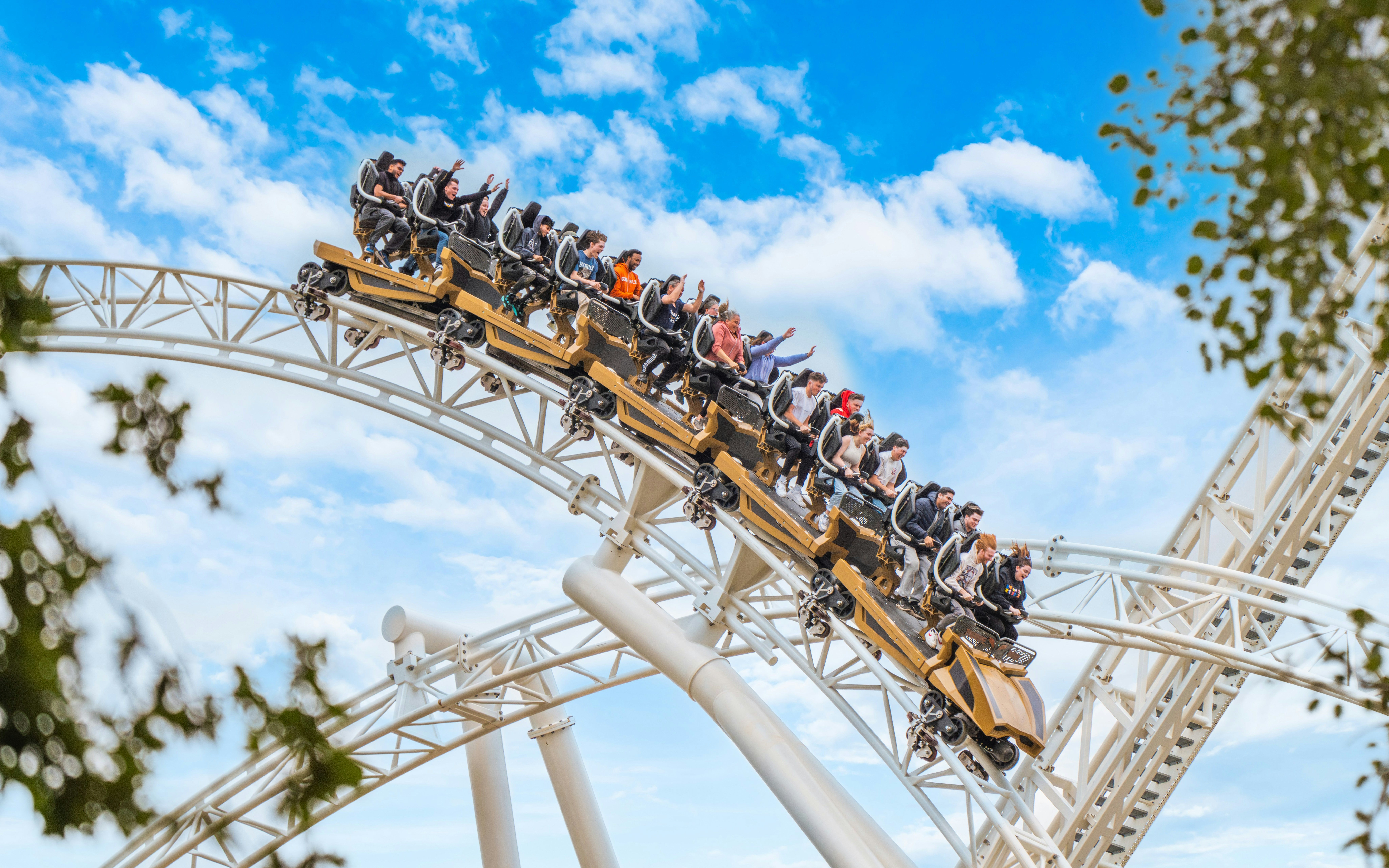 Roller coaster with riders at Thorpe Park against blue sky.