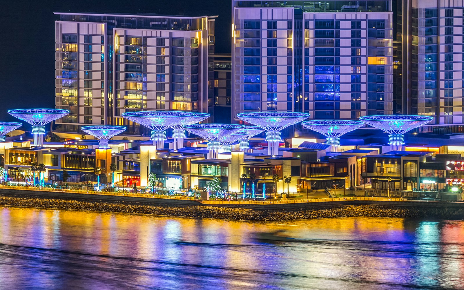 Bluewaters Island Dubai at night with illuminated buildings and water reflections.