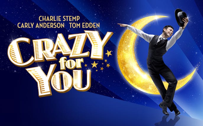 Performer dancing with hat in front of a crescent moon for "Crazy For You" show.