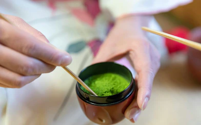 Matcha powder being prepared with a bamboo whisk at a tea ceremony in Kyoto.