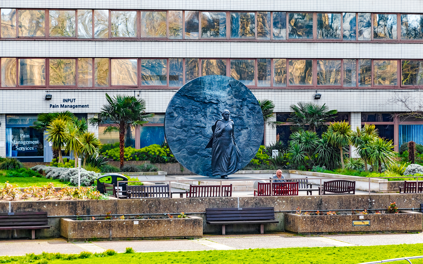 Statue in St Thomas’ Hospital garden, London, with surrounding greenery and benches.