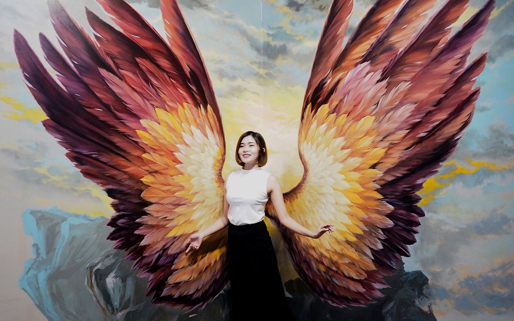 Person posing with angel wings mural at Art in Paradise Pattaya.