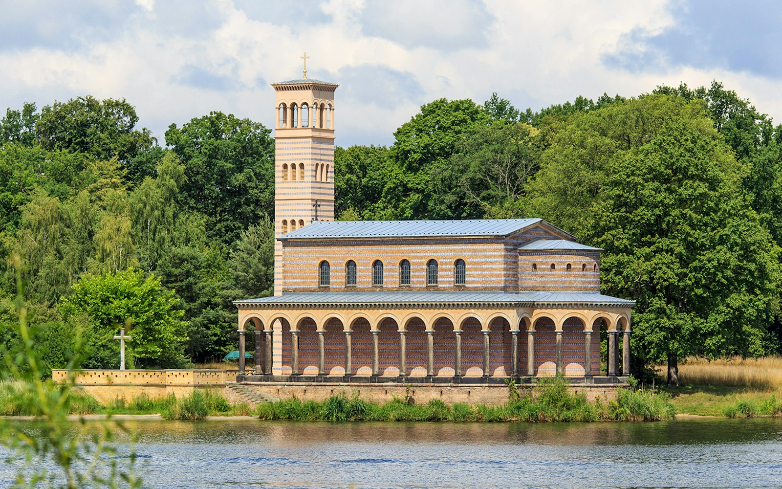 Church of the Redeemer by the water at Sacrow port, surrounded by trees.