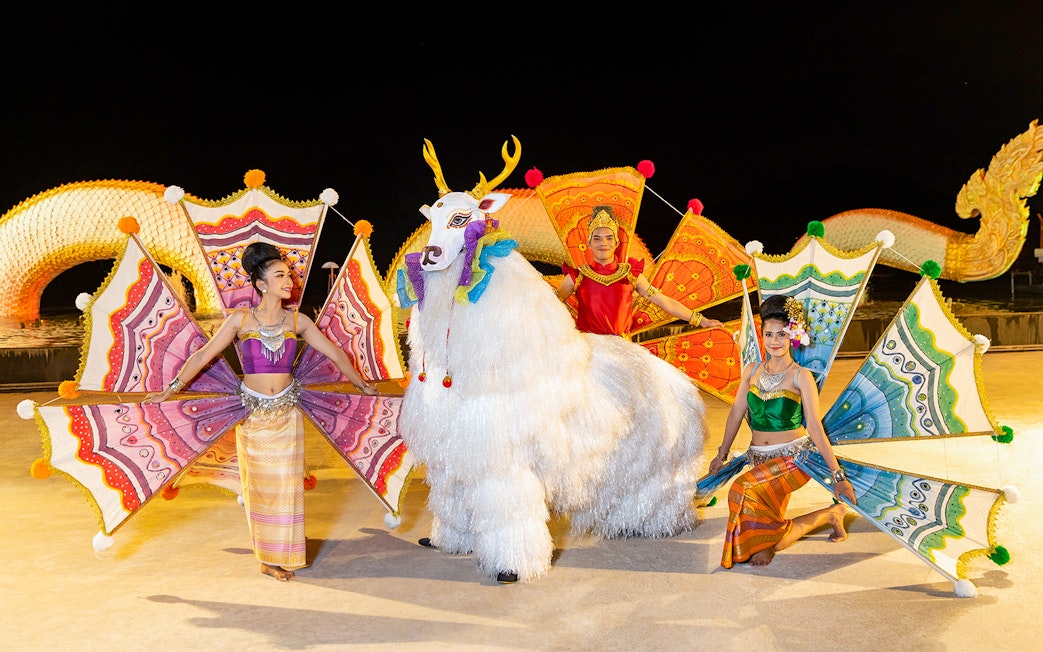 Performers in colorful costumes at Siam Niramit preshow with mythical creature.