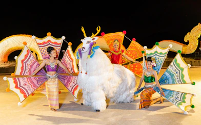Performers in colorful costumes at Siam Niramit preshow with mythical creature.