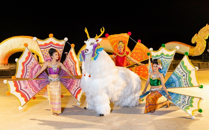 Performers in colorful costumes at Siam Niramit preshow with mythical creature.