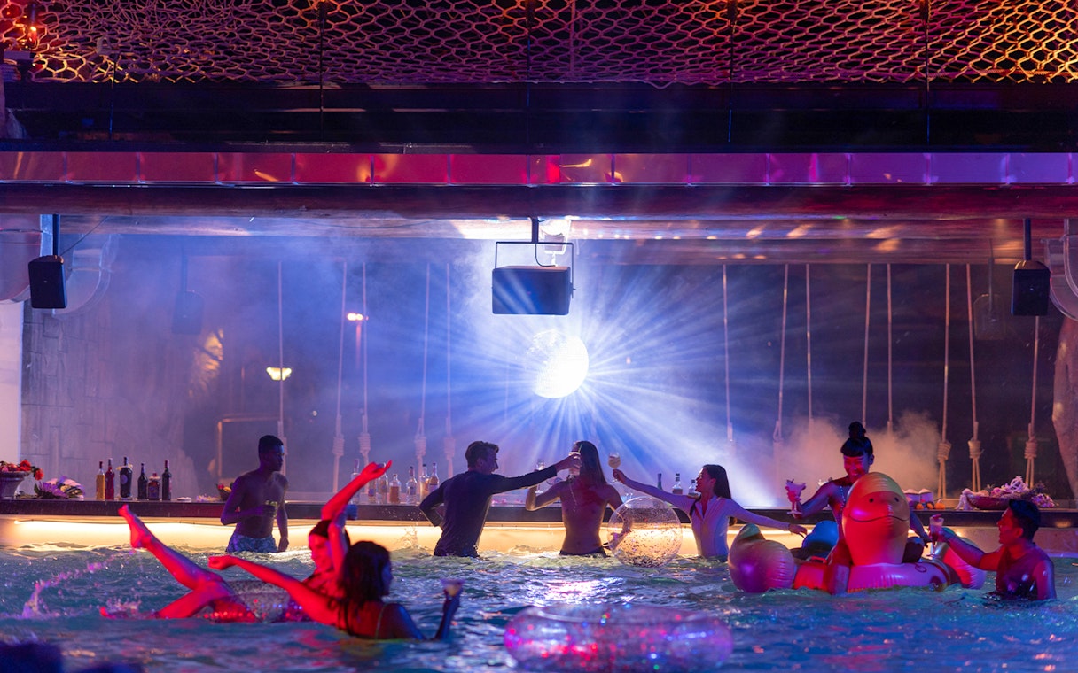 People enjoying a pool party with drinks and inflatables at Andamanda Phuket.