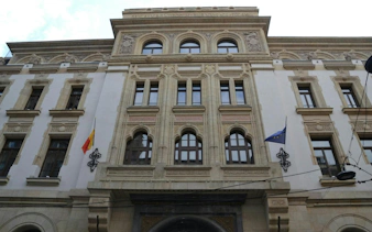 Historic building facade with Romanian and EU flags, part of Jewish Bucharest exploration game.