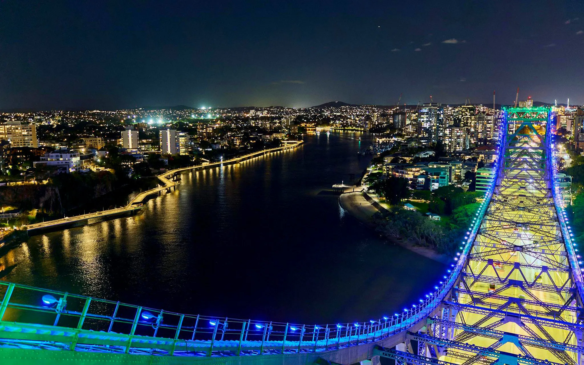 Story Bridge lit up at night with Brisbane city skyline in the background.