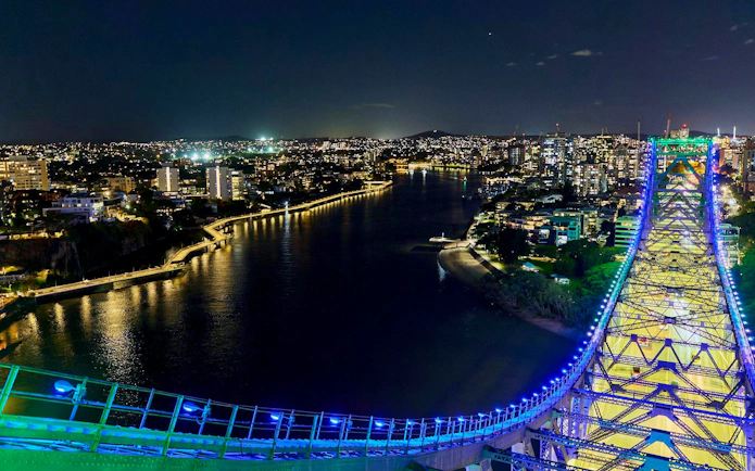 Story Bridge lit up at night with Brisbane city skyline in the background.