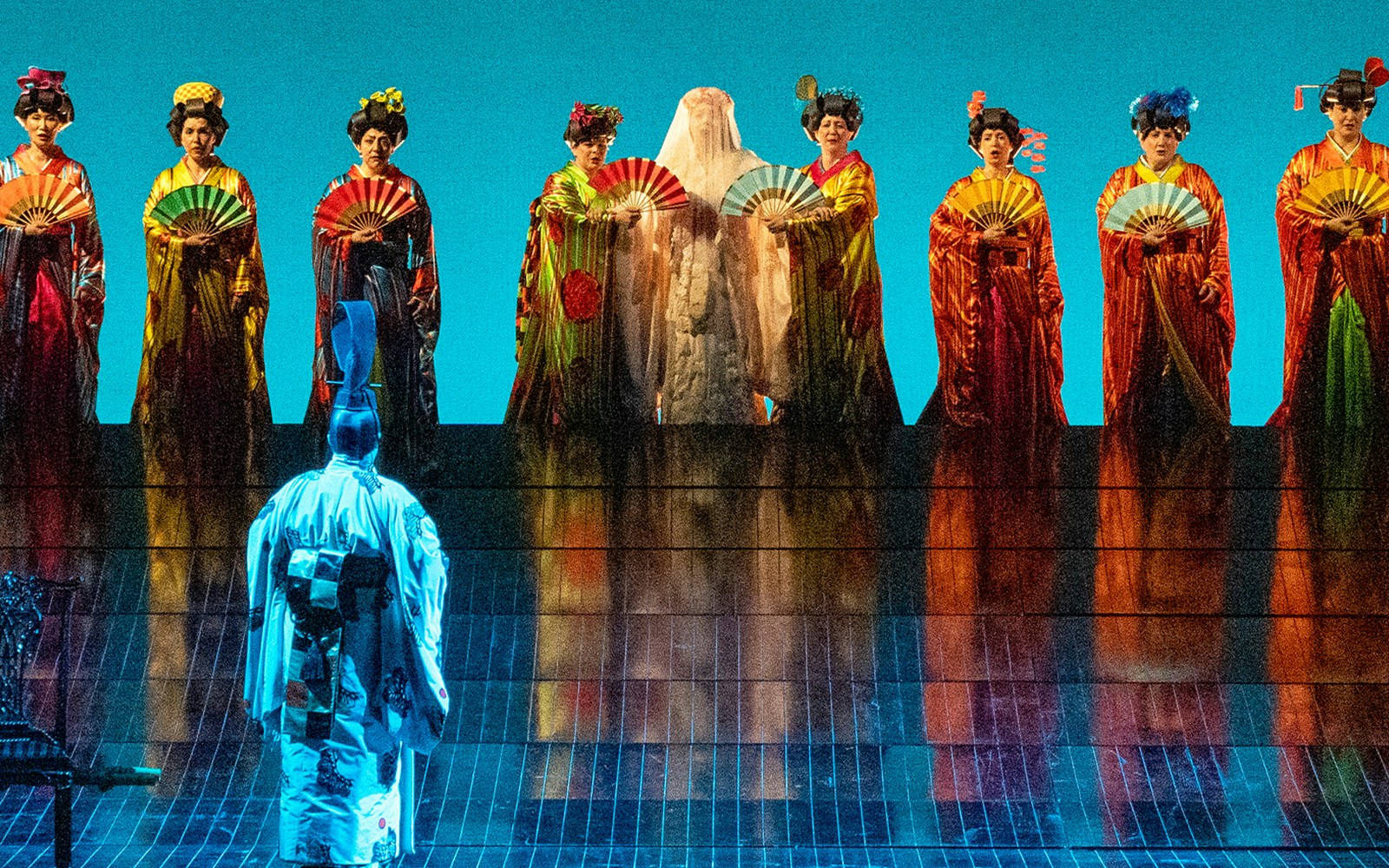 Opera performers in traditional attire with fans on stage during Madama Butterfly.